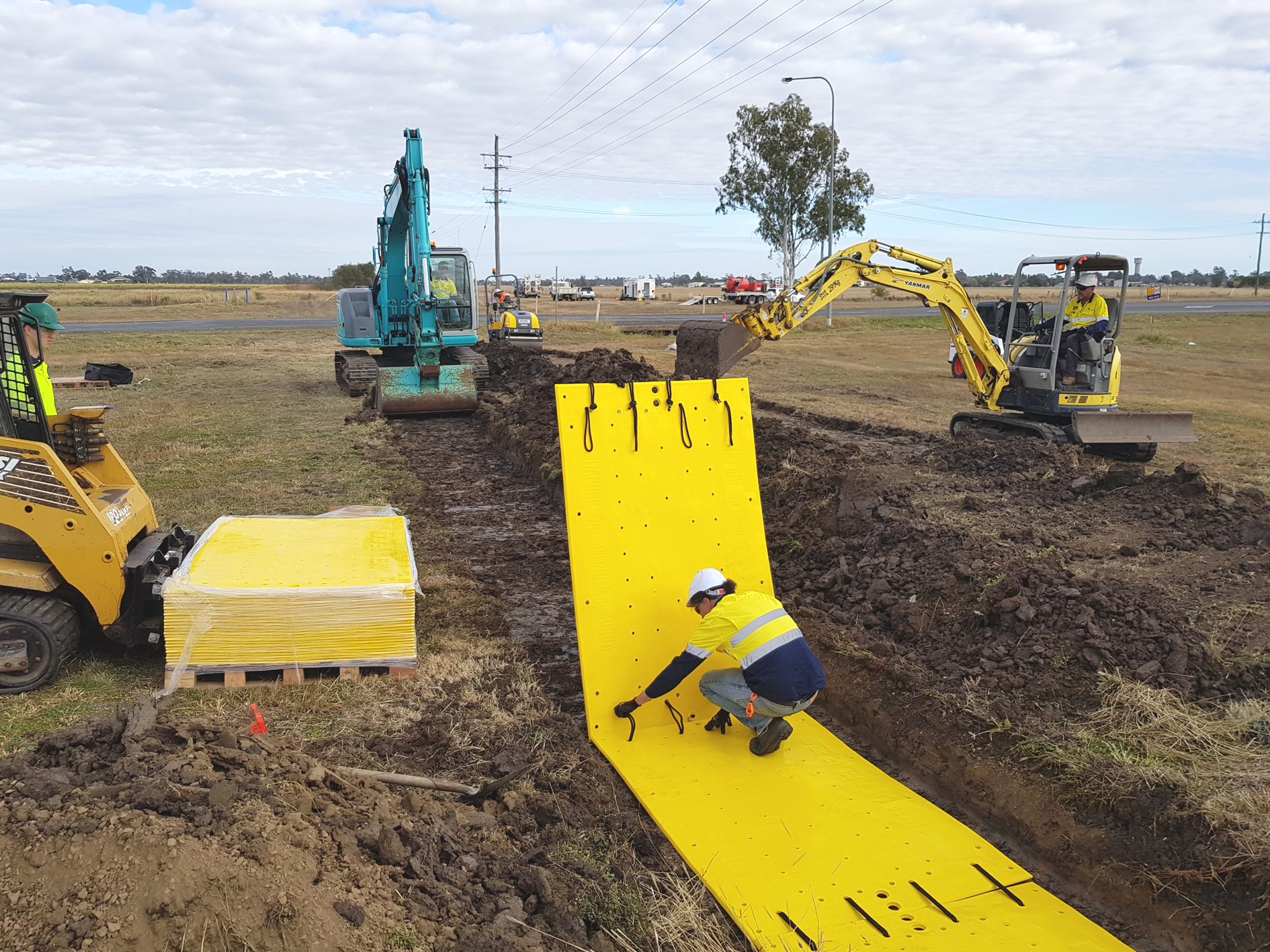 a man in a yellow helmet and hard hat working on overpipe protection plates